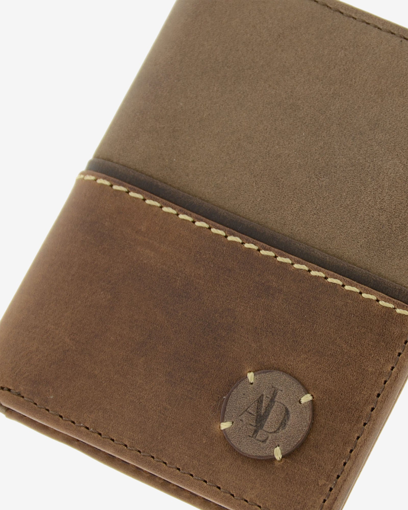Detalle de cartera de hombre colección Rancho en piel rústica bicolor marrón con logo circular Adapell grabado y cosido, y costura decorativa contrastada. Ref. 1605-2