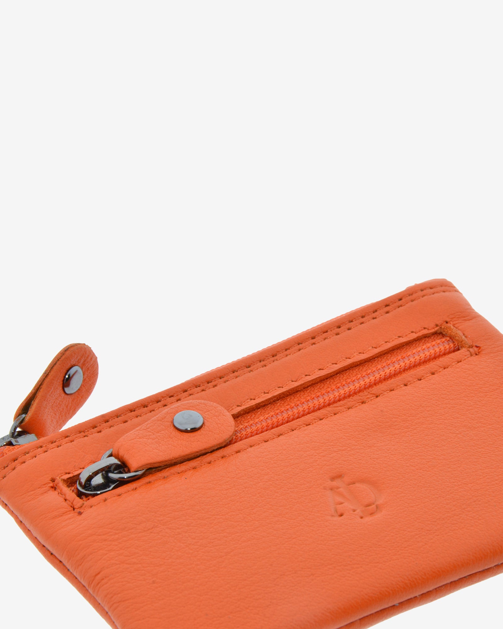 Detalle de la textura de la piel, las costuras, la cremallera frontal y el logo del monedero 8010 en color mandarina.