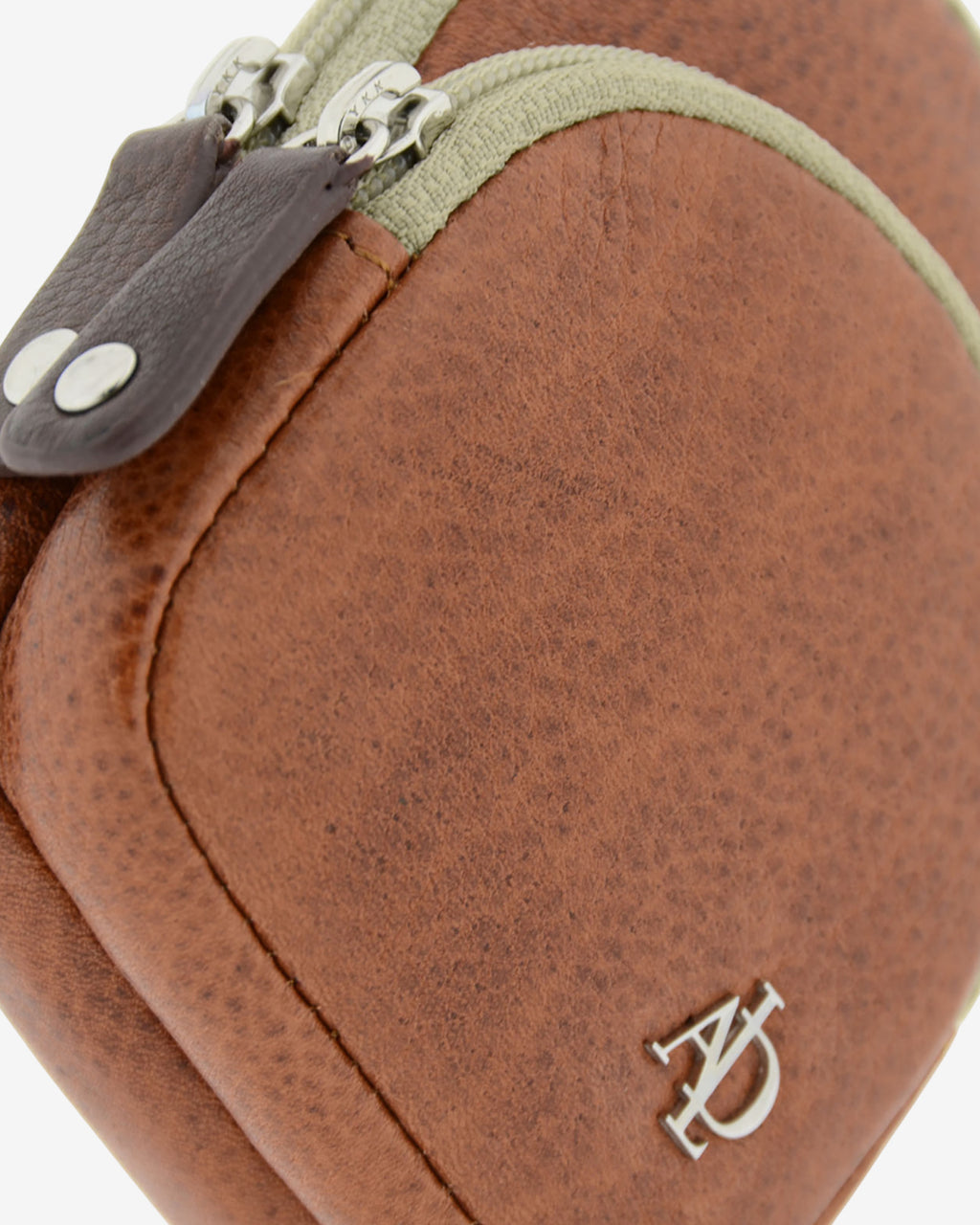 Detalle frontal del monedero llavero Adapell 8077-V en color marrón, con forma de mini mochila, mostrando la textura de la piel, las cremalleras y el logo metálico.