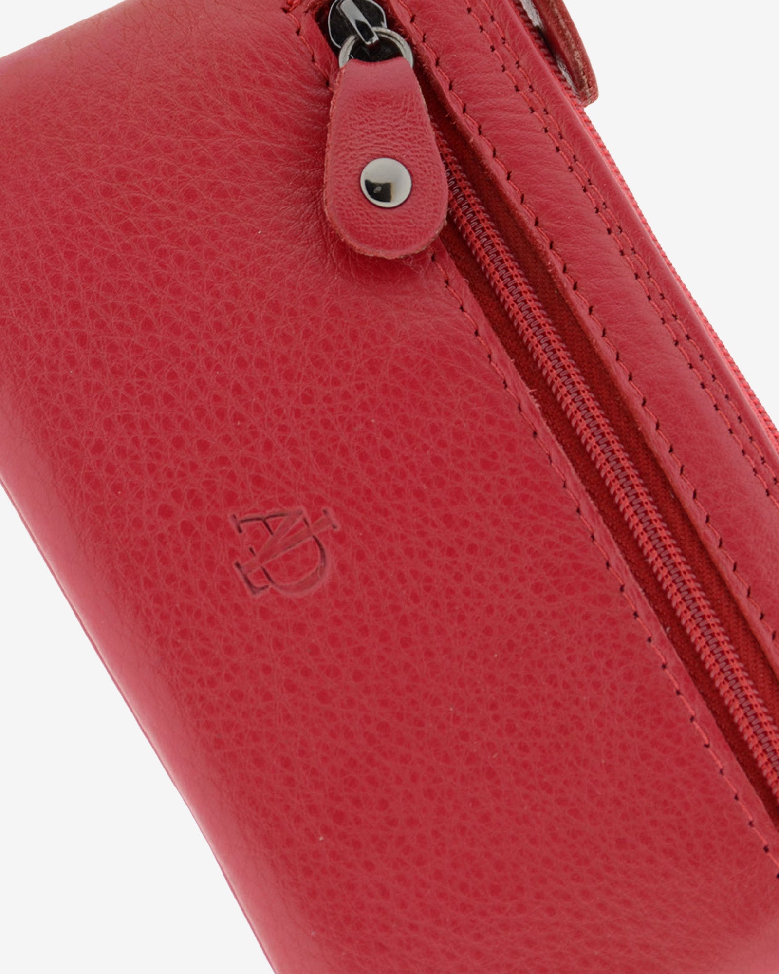 Detalle de la textura de la piel, el logo grabado y la cremallera frontal del monedero 8079 en color rojo.
