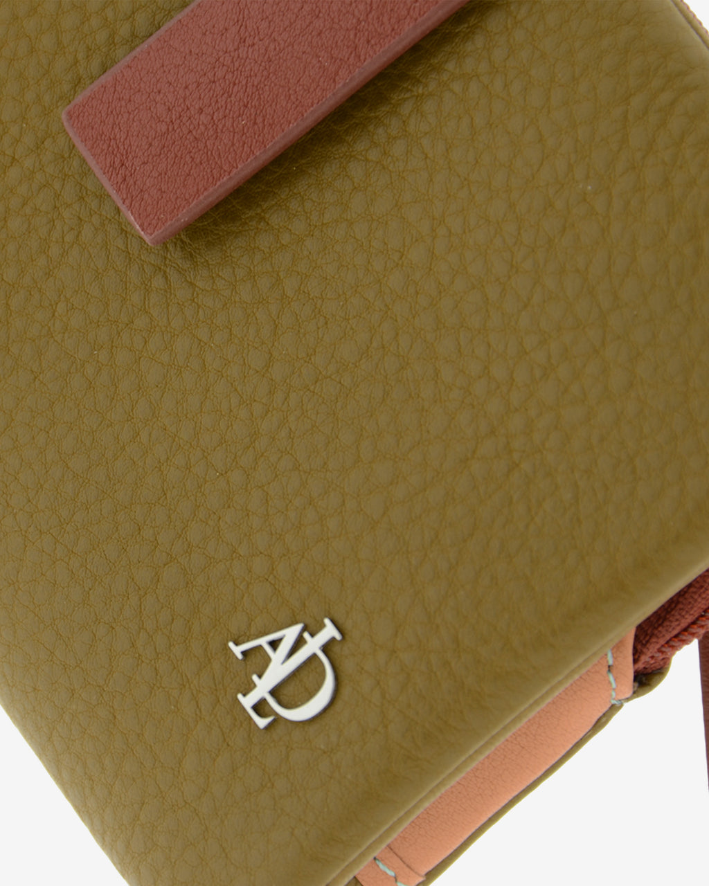 Primer plano de la cartera Brisa en color Ámbar Ébano mostrando la textura de la piel, la tira de cierre en contraste y el logo metálico Adapell.
