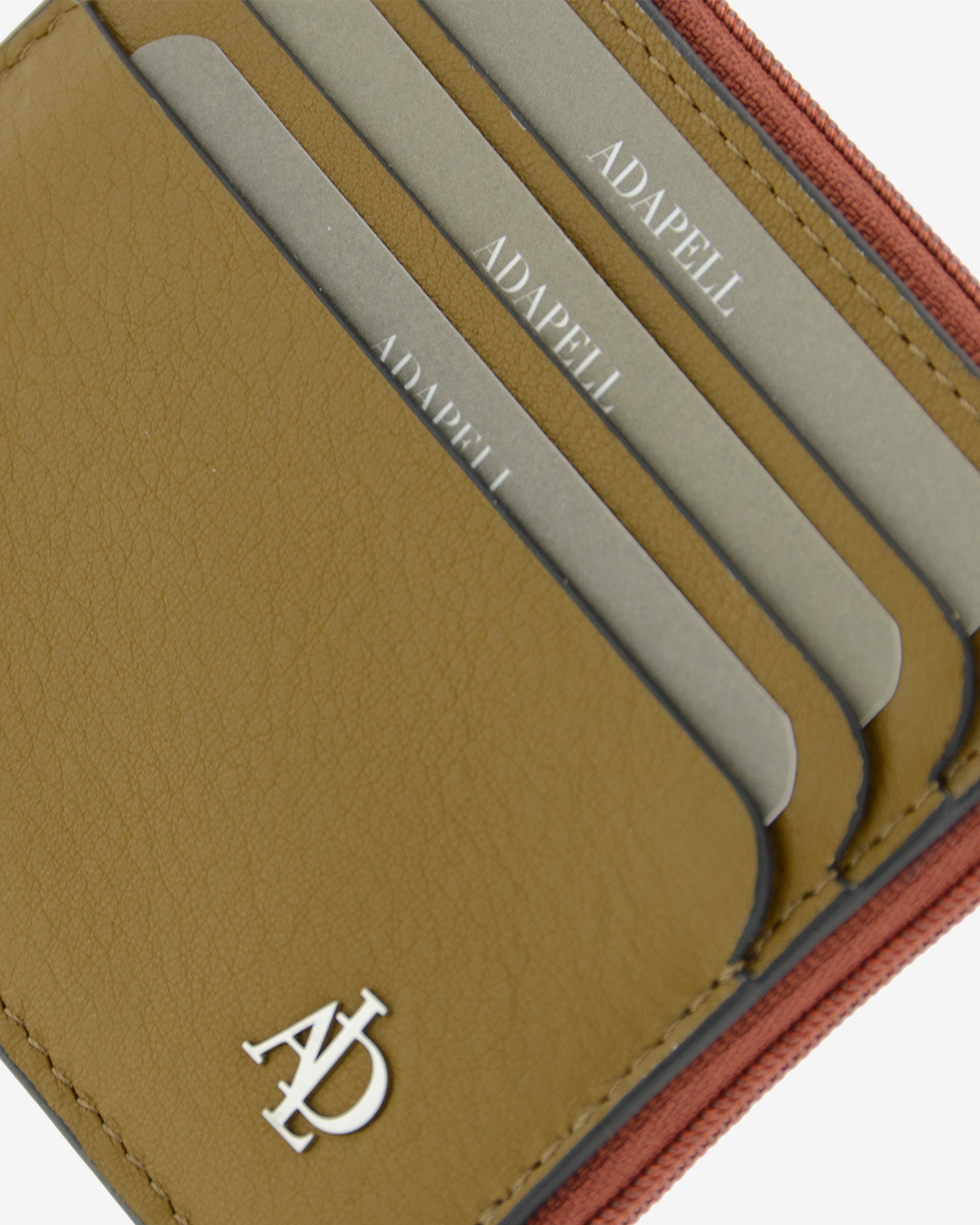 Detalle de las ranuras exteriores para tarjetas, el logo metálico Adapell y la cremallera del tarjetero Brisa en color Ámbar Ébano.