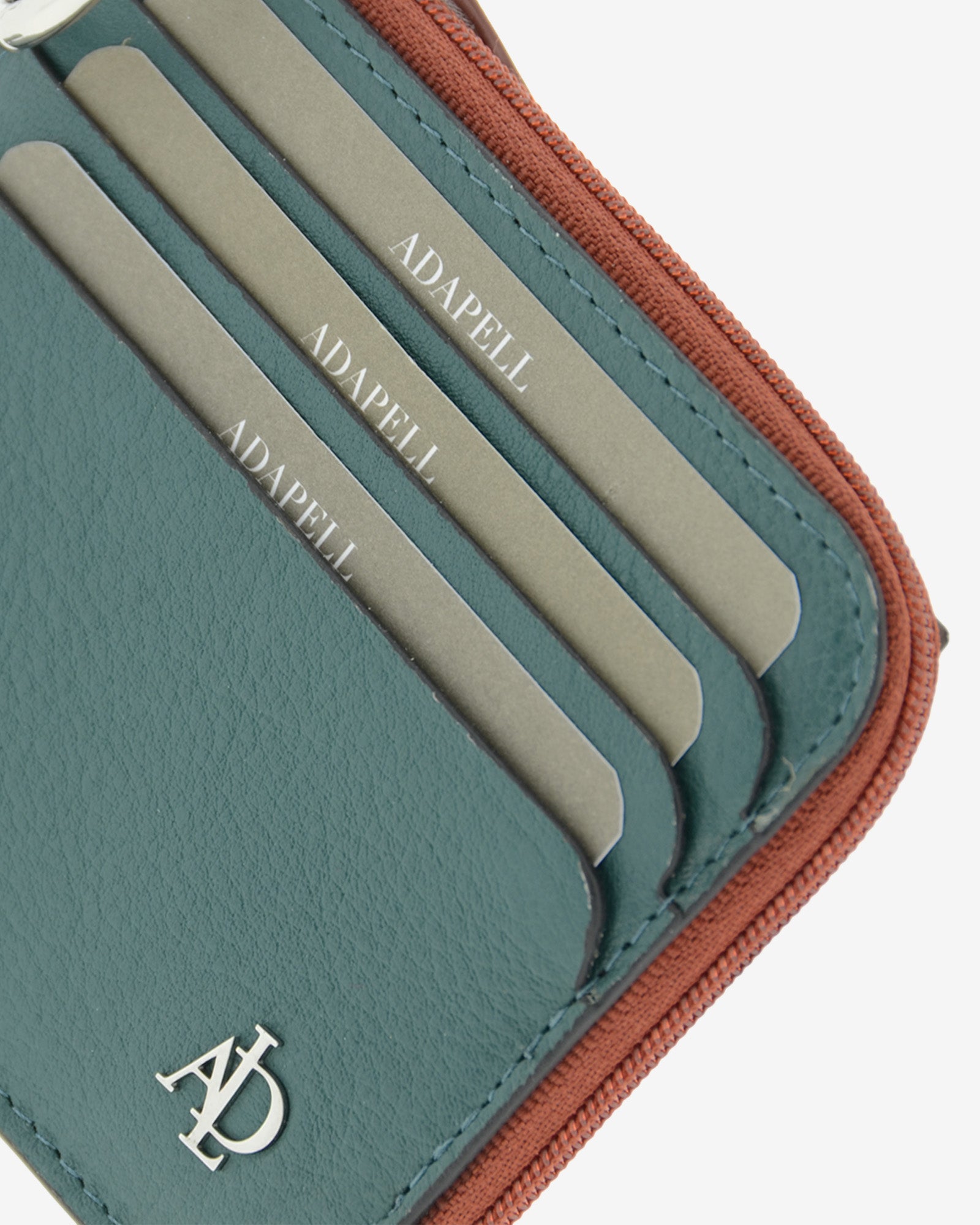 Detalle de las ranuras exteriores para tarjetas, el logo metálico Adapell y la cremallera del tarjetero Brisa en color Ocean Teal.
