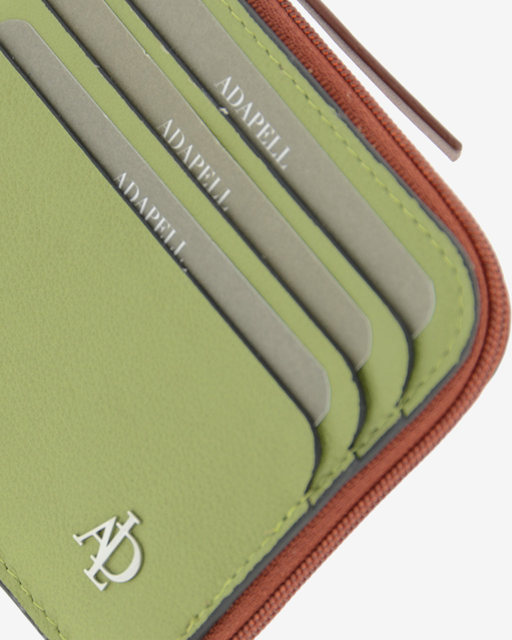 Detalle de las ranuras exteriores para tarjetas, el logo metálico Adapell y la cremallera del tarjetero Brisa en color Verde Sage.