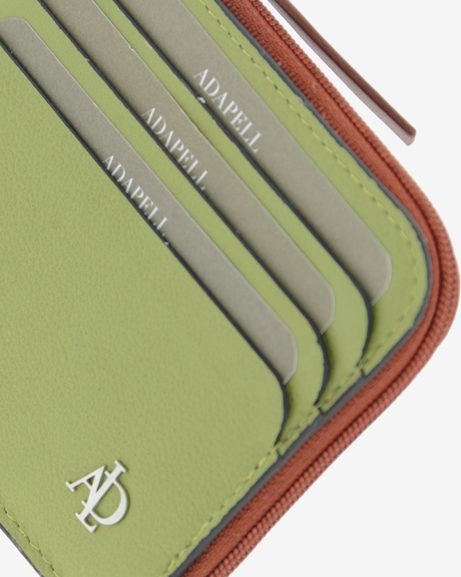 Detalle de las ranuras exteriores para tarjetas, el logo metálico Adapell y la cremallera del tarjetero Brisa en color Verde Sage.