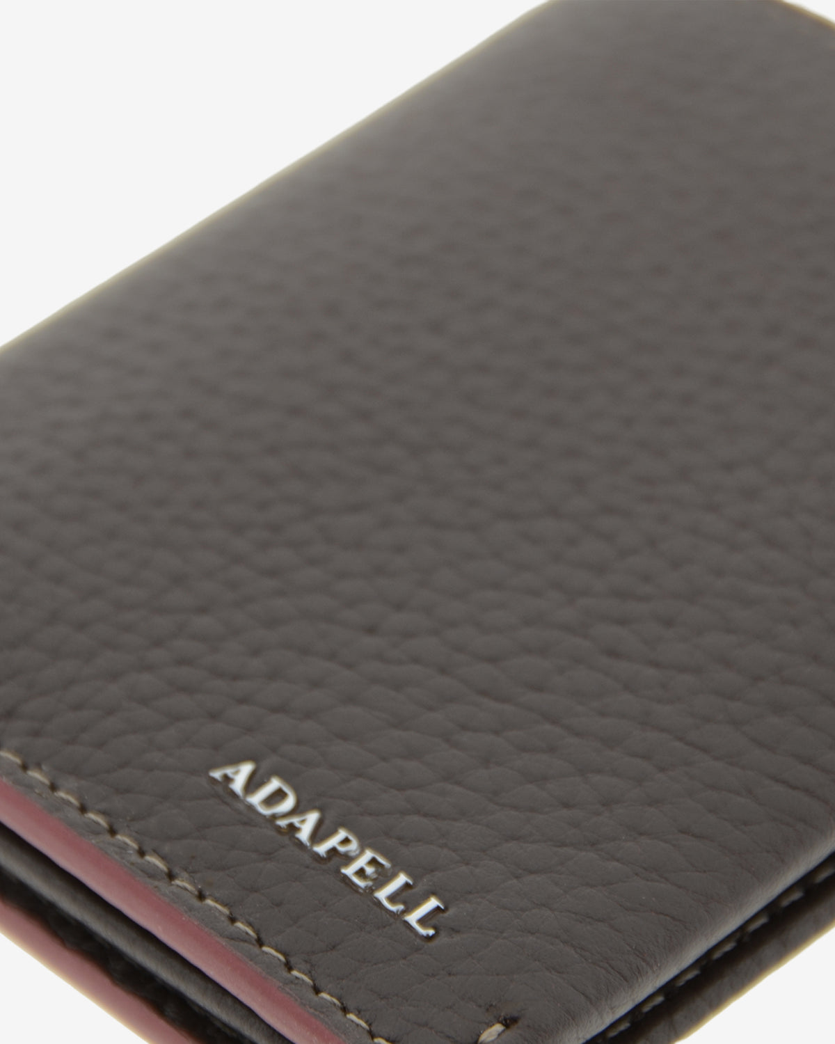 Primer plano de la piel granulada y el logo ADAPELL de la cartera vertical Nexo 1670 chocolate.