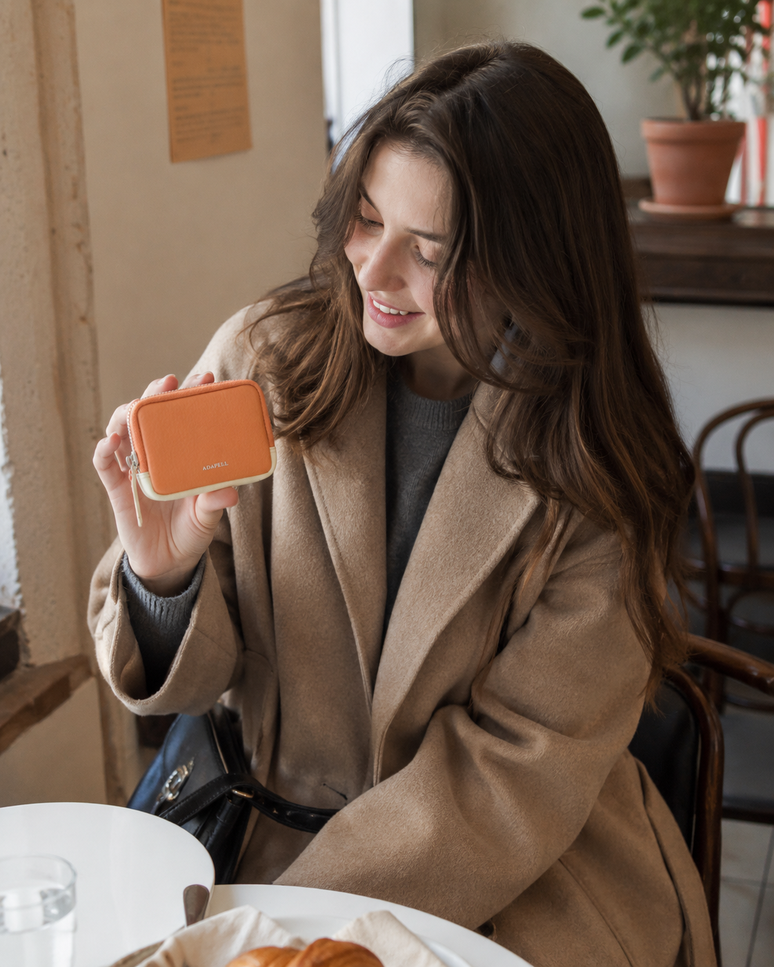 Mujer sosteniendo el monedero de piel Nexo 8095 en color miel, diseñado para llevar monedas y tarjetas en un formato pequeño con cierre de cremallera.