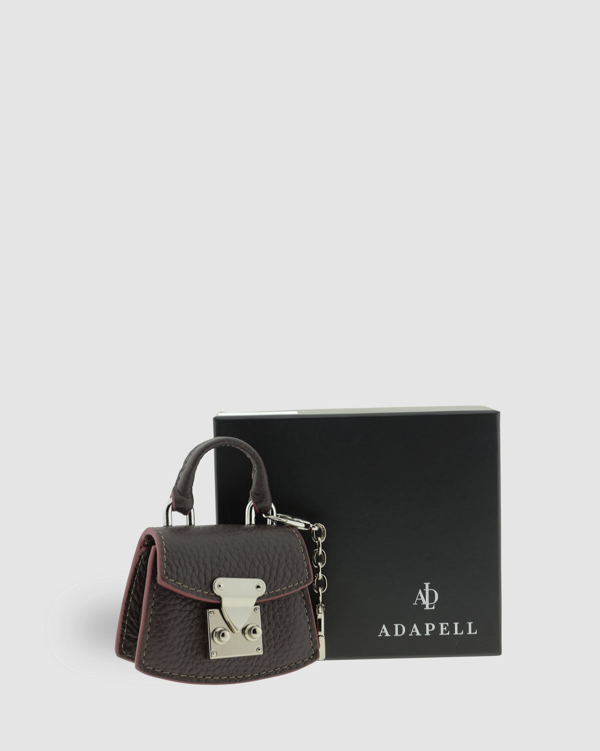 Charm para bolso con funda para auriculares Nexo 8099 chocolate presentado junto a la caja Adapell