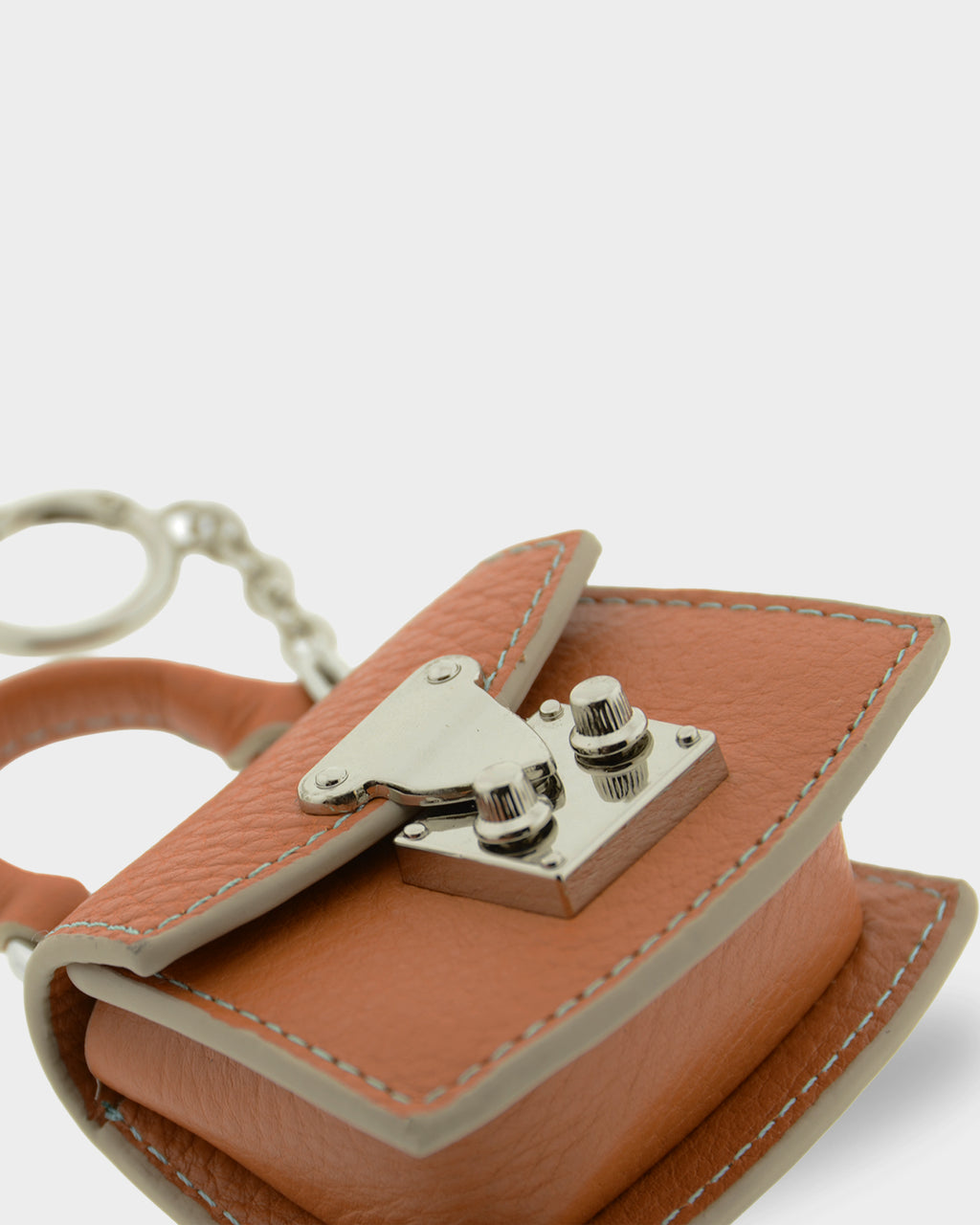 Detalle frontal tumbado del charm para bolso con funda para auriculares Nexo 8099 miel con solapa y cierre metálico