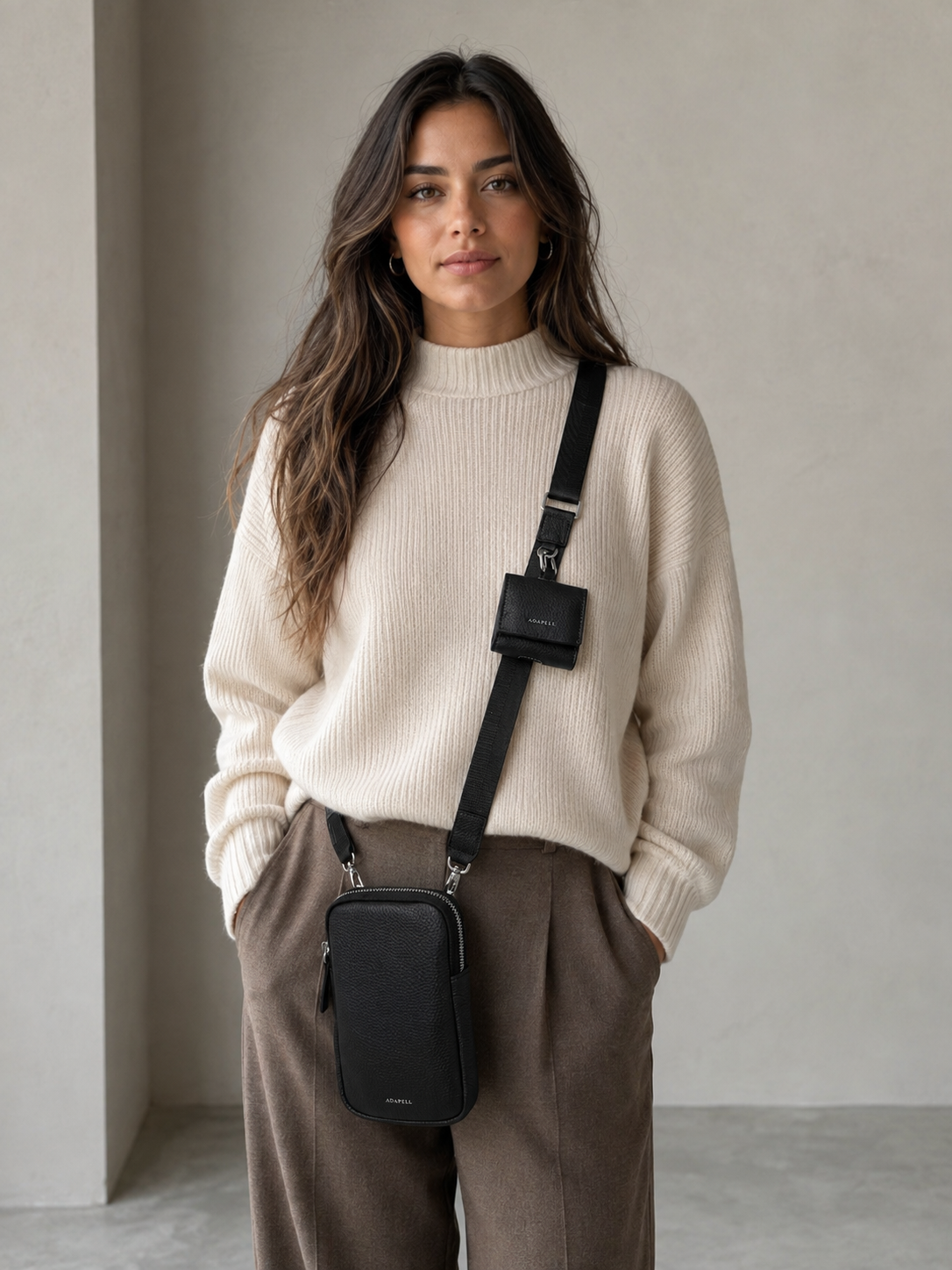 Mujer joven con funda para auriculares Nexo 8093 en color negro acoplada a la bandolera de un bolso Nexo negro sobre fondo neutro