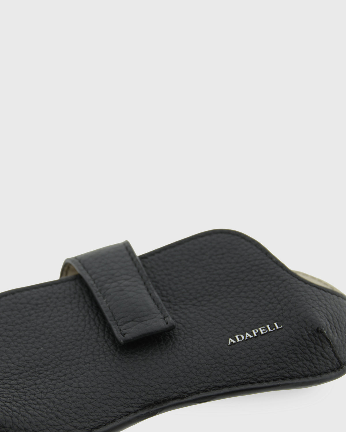 Detalle frontal de la funda para gafas Nexo 8094 negro en posición horizontal, mostrando la piel granulada, la tira de sujeción y el logo Adapell