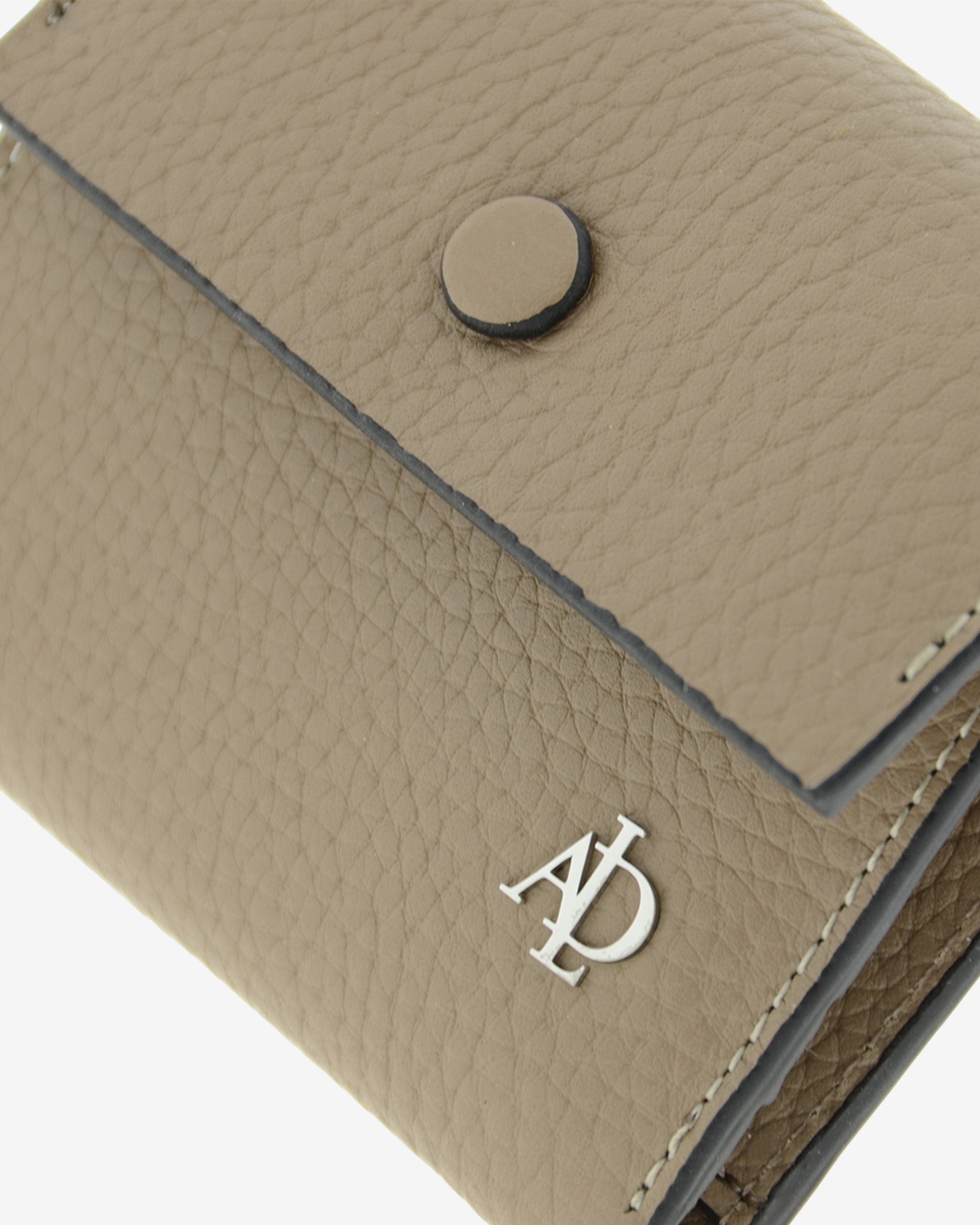 Detalle de la cartera pequeña Nude 4256 en color Topo con botón a presión, textura granulada, costuras y logo metálico Adapell.