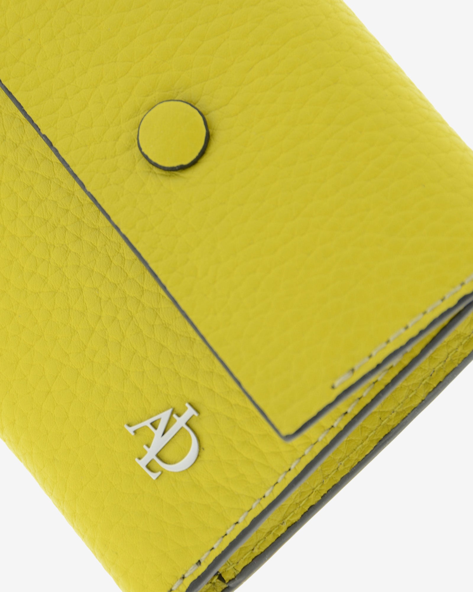 Detalle frontal de la cartera pequeña Nude en color Citrine con solapa, botón, costuras, textura de la piel y logo Adapell.
