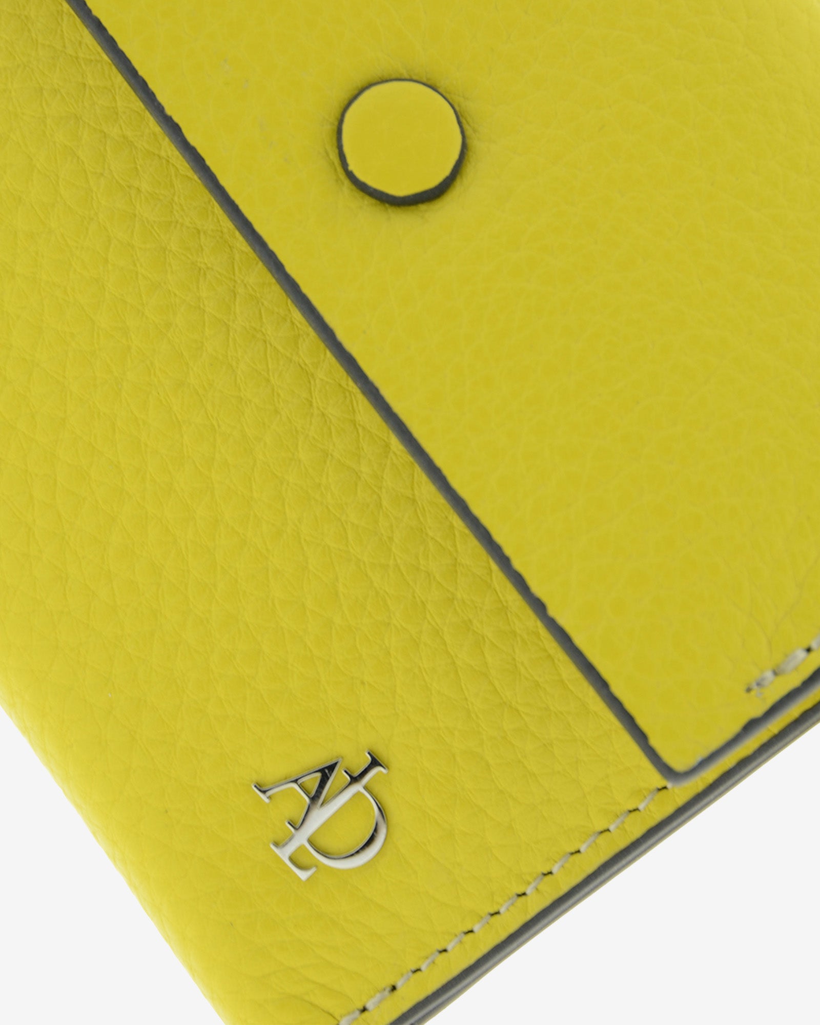 Detalle de la solapa con botón a presión, la textura de la piel y el logo metálico Adapell de la cartera Nude en color Citrine.