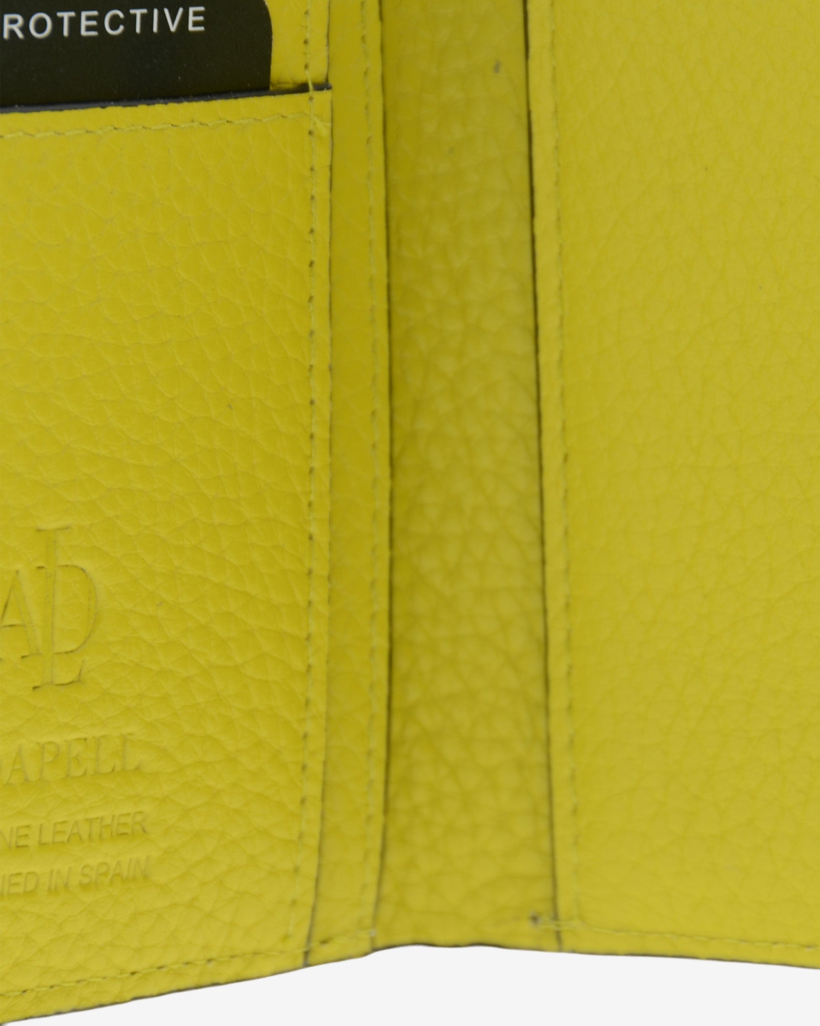 Detalle interuior de la cartera, la textura de la piel y el logo metálico Adapell de la cartera Nude en color Citrine.