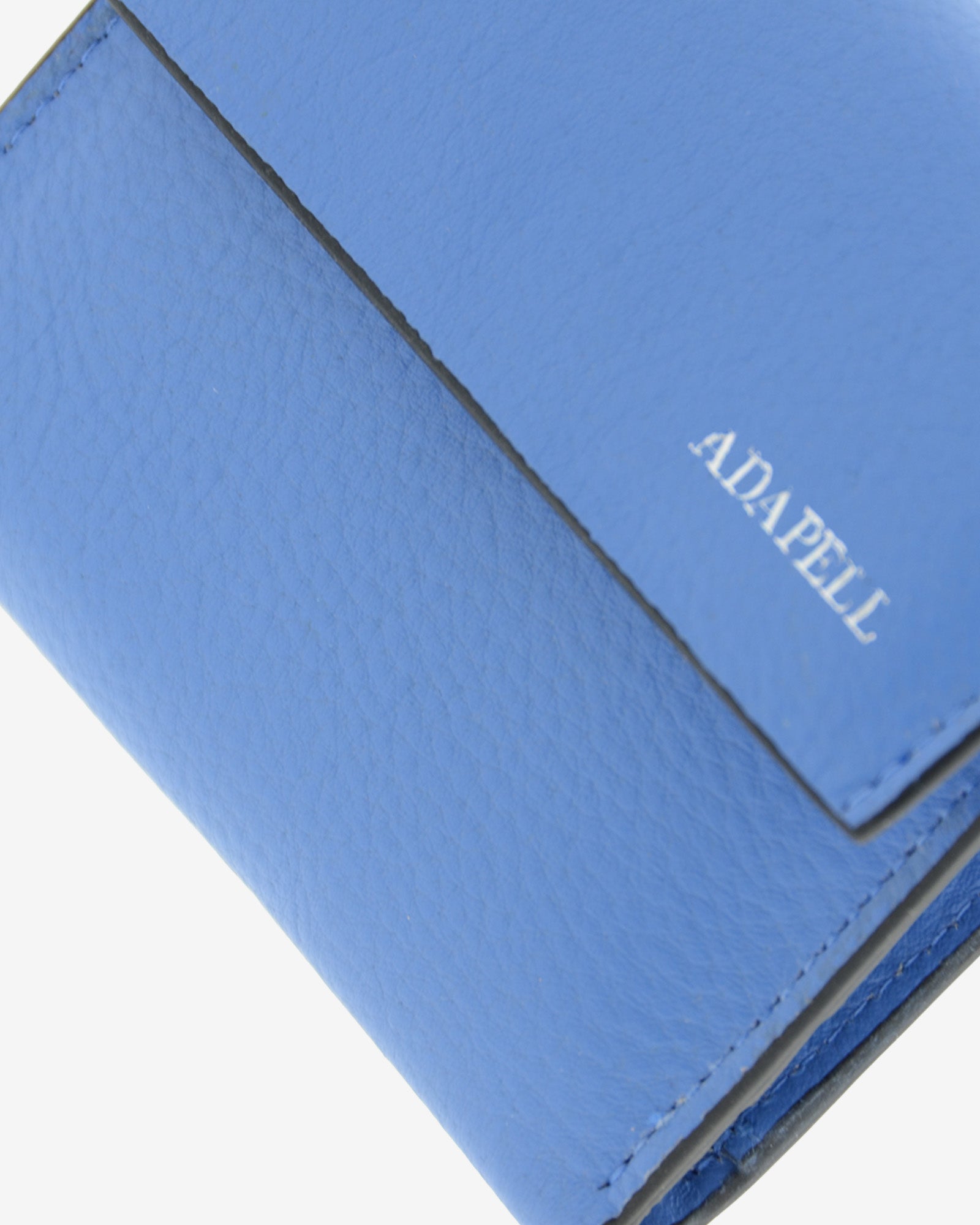 Cartera de piel auténtica ref. 8080-14 en color azul y ribete negro, con solapa, de medida pequeña y compacta, con protección de tarjetas RFID de la colección Essenza, vista detalle de piel, acabados y logo Adapell plateado