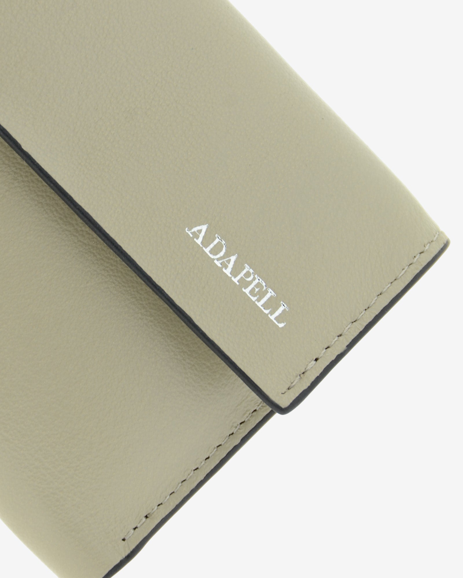 Cartera de piel auténtica ref. 8080-12 en color Ice stone y ribete negro, con solapa, de medida pequeña y compacta, con protección de tarjetas RFID de la colección Essenza, vista detalle de piel, ribetes, costuras y logo Adapell plateado