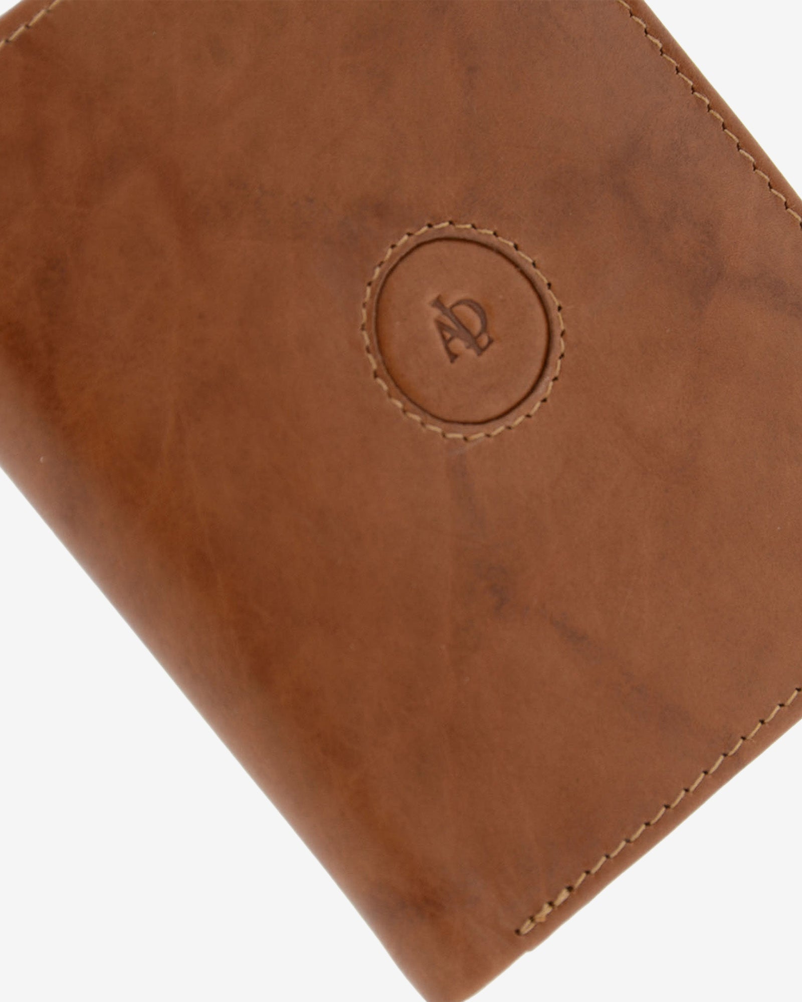 Detalle del logo circular en relieve, pespunte y textura de piel natural color cuero en cartera Adapell, ref. 1592-6
