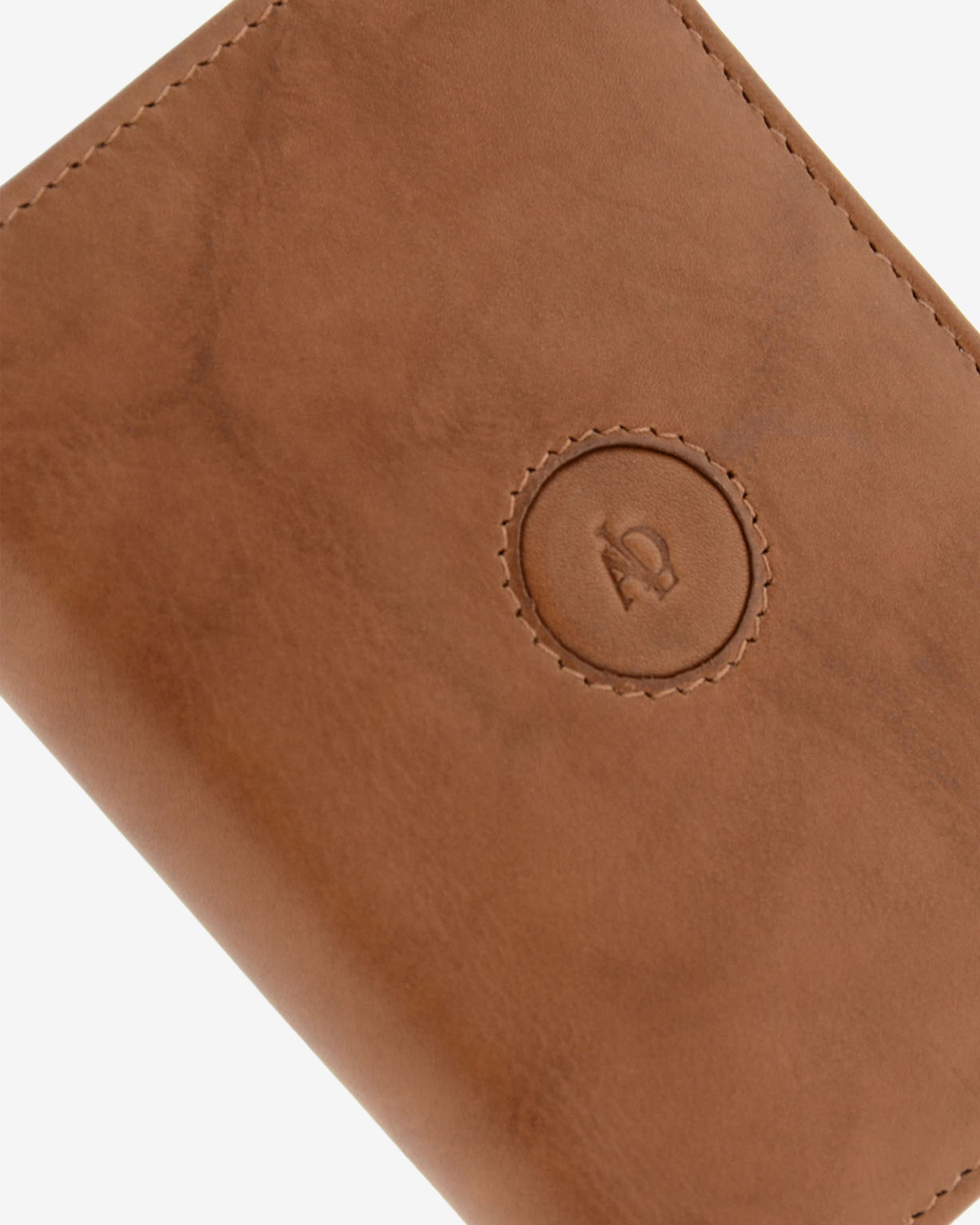Detalle del logo circular en relieve, pespunte y textura de piel natural color cuero en cartera Adapell, ref. 1591-6