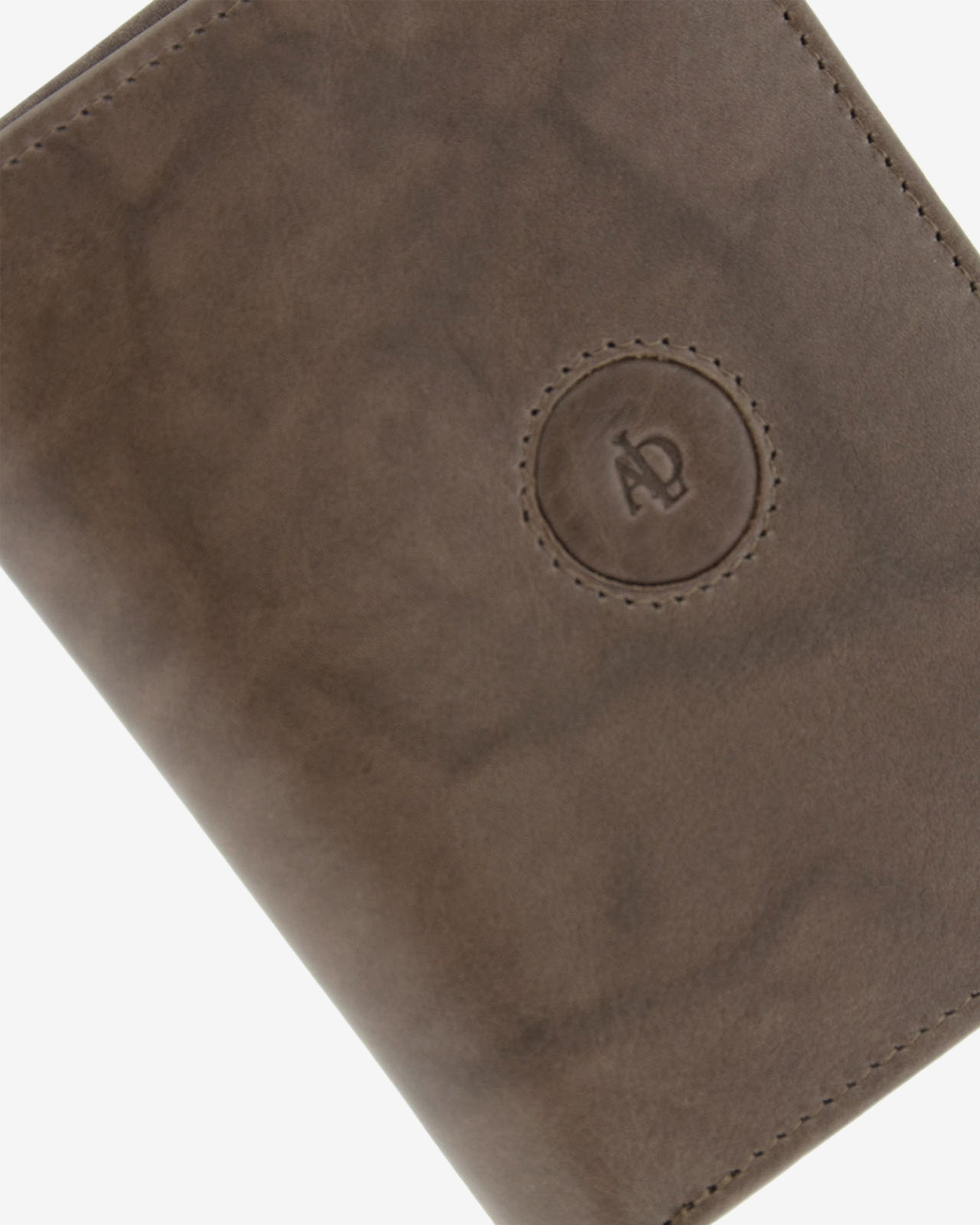 Detalle del logo circular en relieve, pespunte y textura de piel natural color gris en cartera Adapell, ref. 1591-11