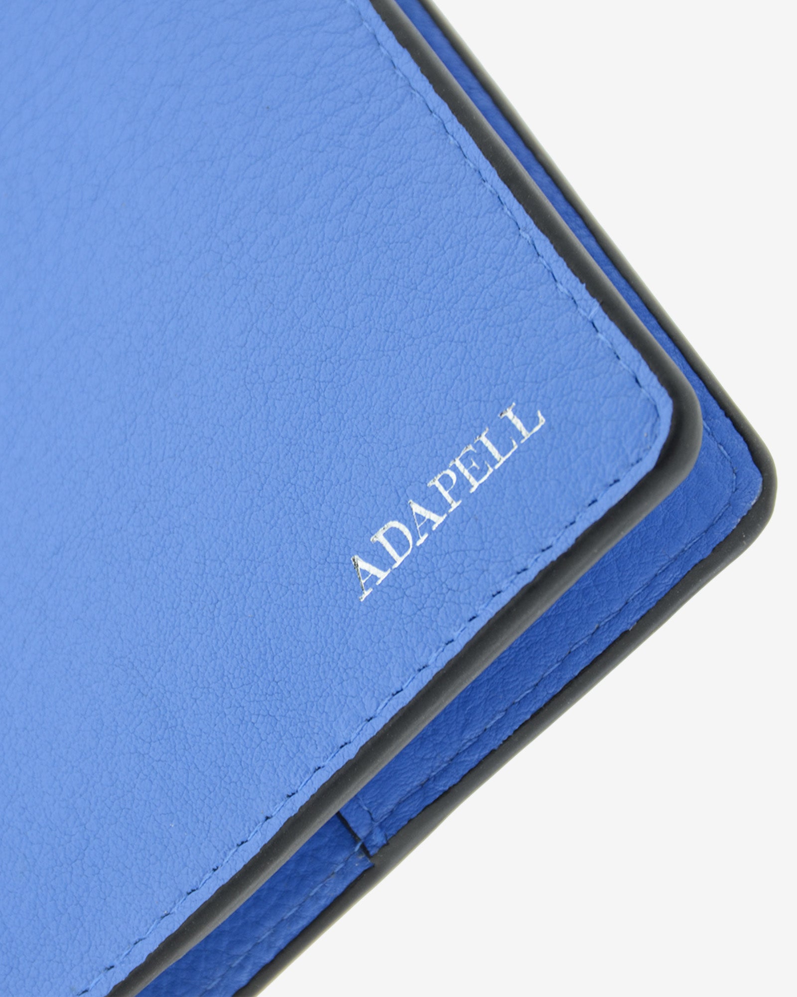 Funda pasaporte en piel auténtica muy suave de color azul y cantos en negro, ref. 8087-14, con protección RFID, y logo plateado Adapell, vista detalle de piel y acabados premium