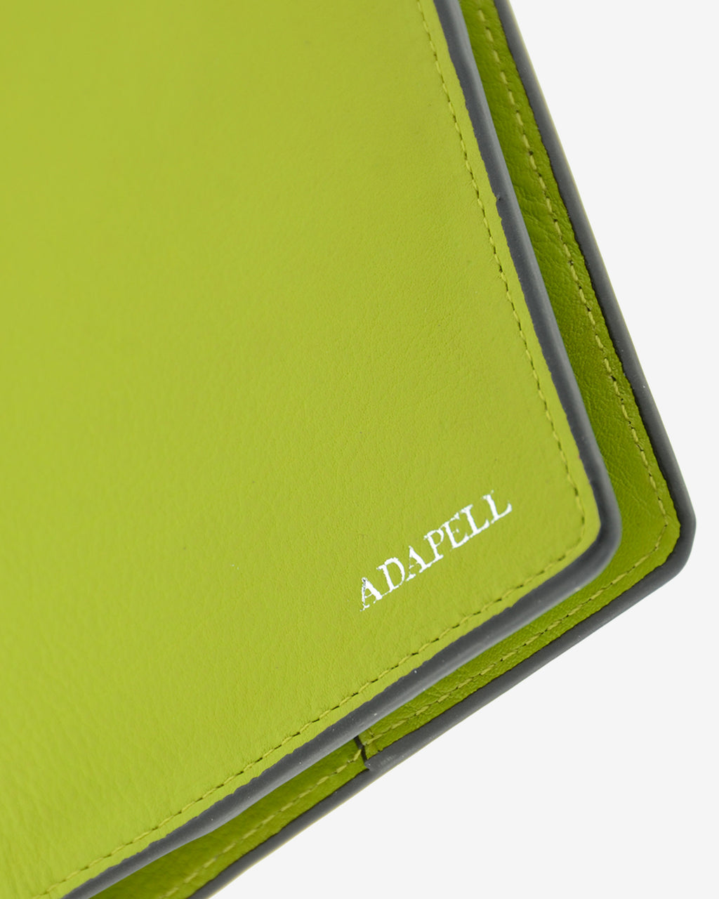 Funda pasaporte en piel auténtica muy suave de color lima y cantos en negro, ref. 8087-17, con protección RFID, y logo plateado Adapell, vista detalle de piel y acabados