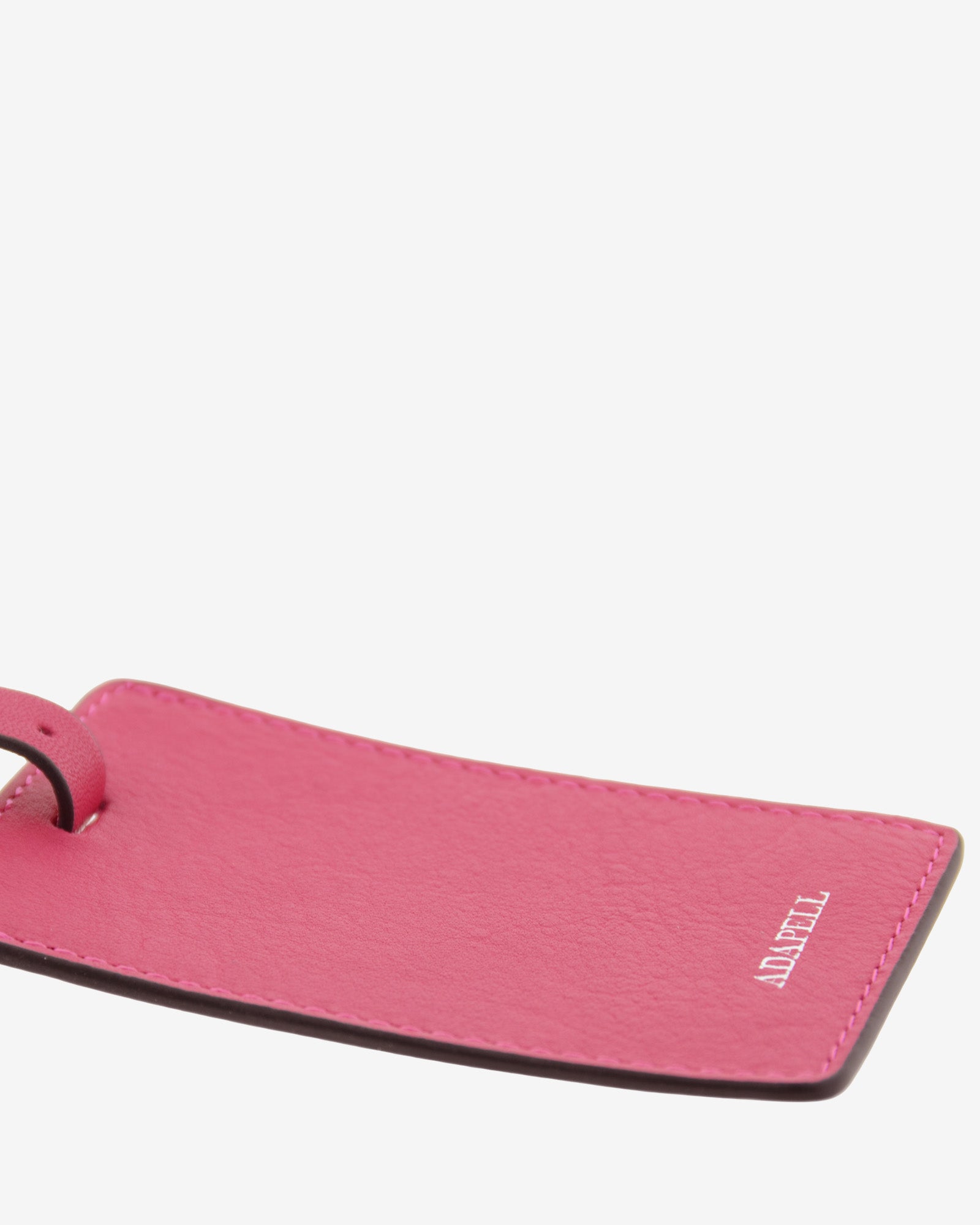 Tag identificador maleta con cierre de hebilla, ref. 8088-25, en piel de color fucsia y cantos en negro, con logo Adapell, vista detalle de piel y acabados